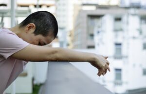 una donna si appoggia stanca al balcone di un edificio affetto da sindrome edificio malato chiamata anche sick building syndrome